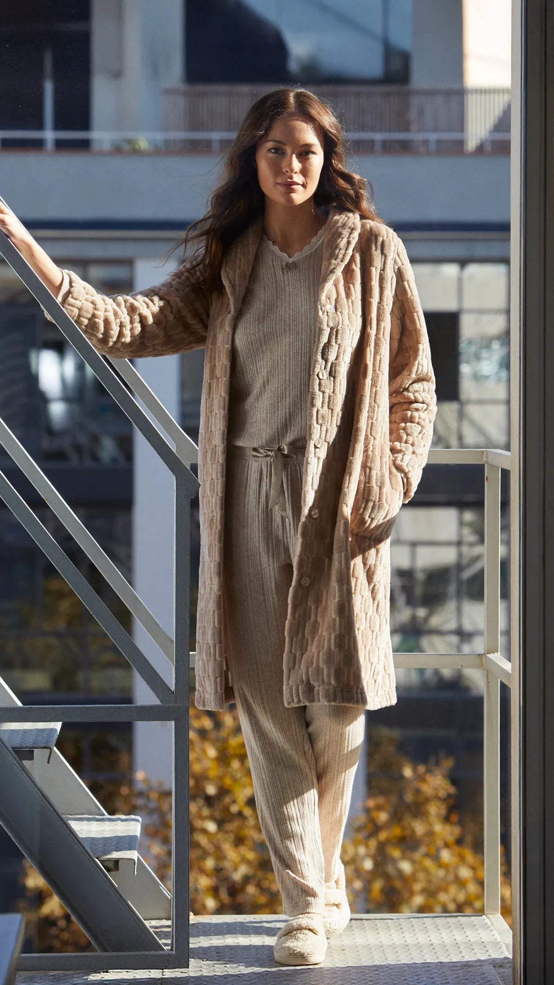 Mujer lleva bata beige texturizada y conjunto de pijama canale camel y pantuflas