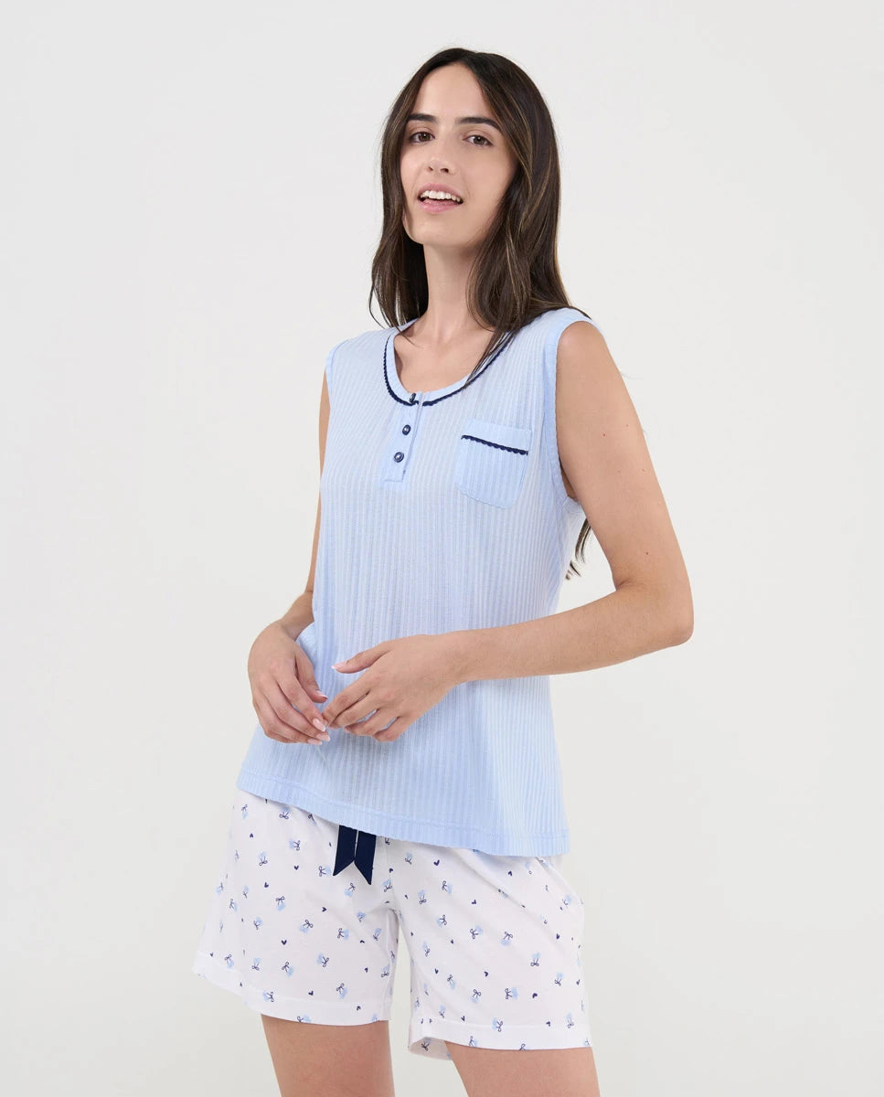 Mujer con pijama de verano corto sin mangas en punto celeste acanalado y pantalón blanco de cerezas.