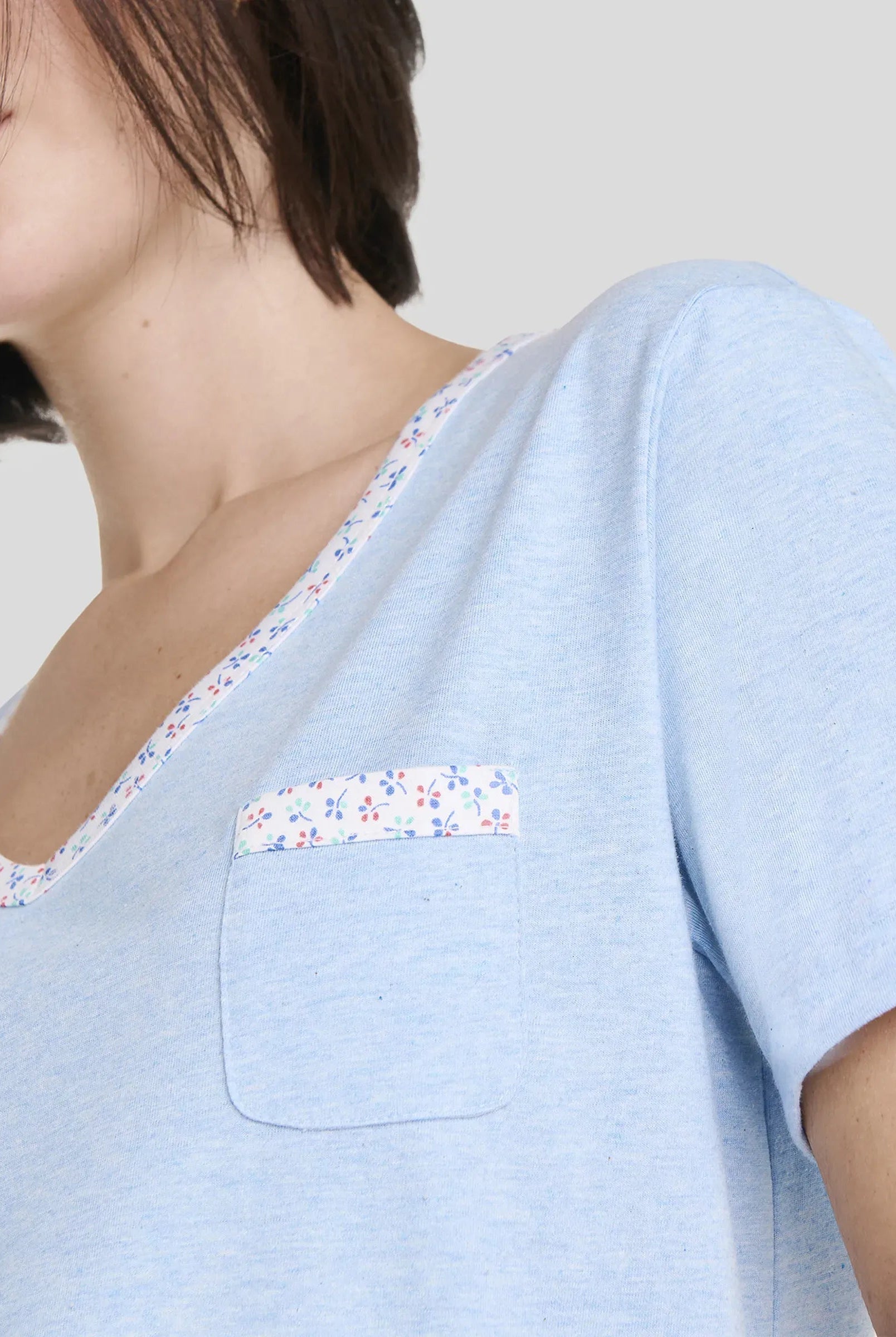 Detalle de camiseta de pijama de manga corta azul con detalles de florecillas en cuello pico y bolsillo