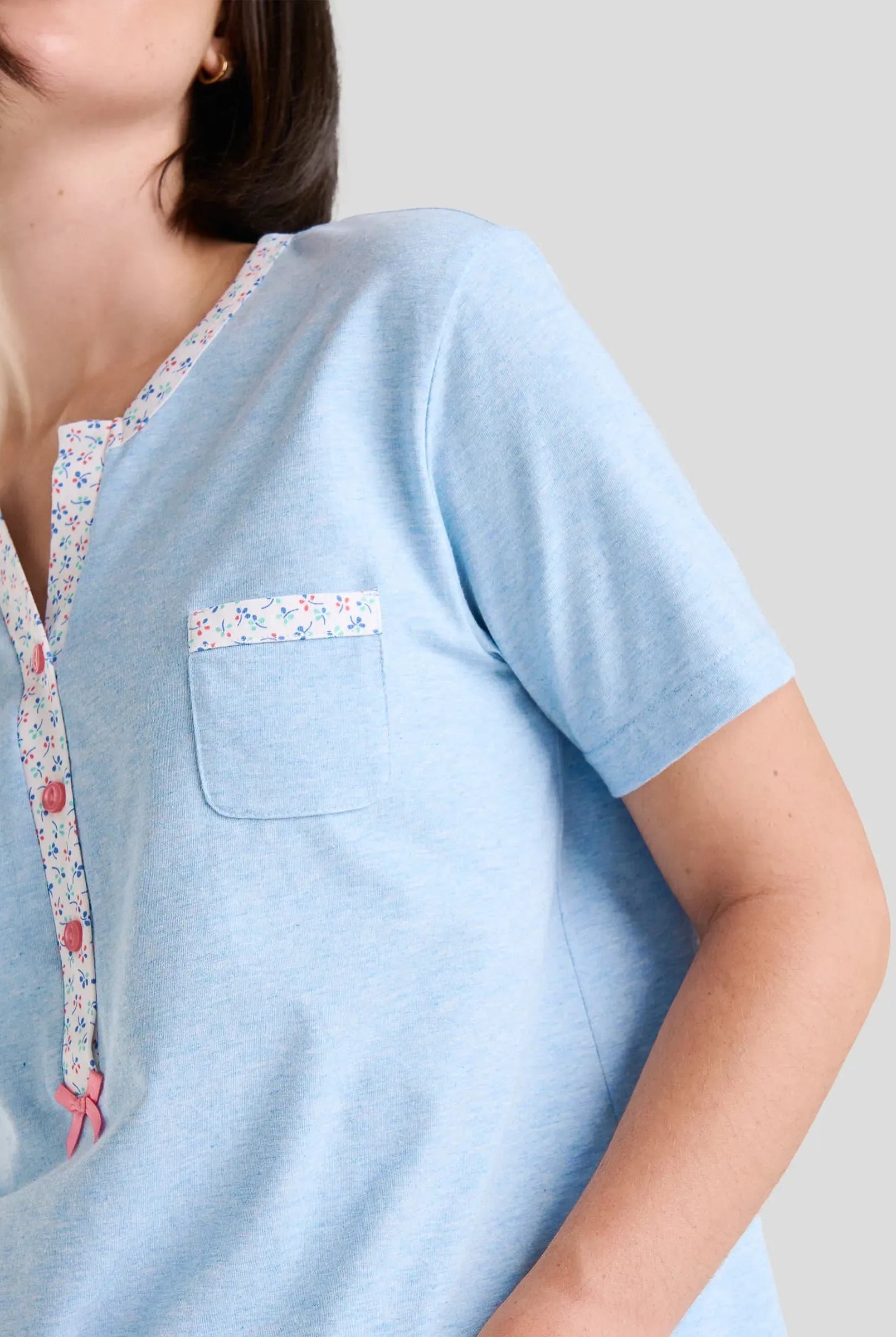 Detalle de cuello abierto con pata de florecitas y botones de pijama de manga corta celeste
