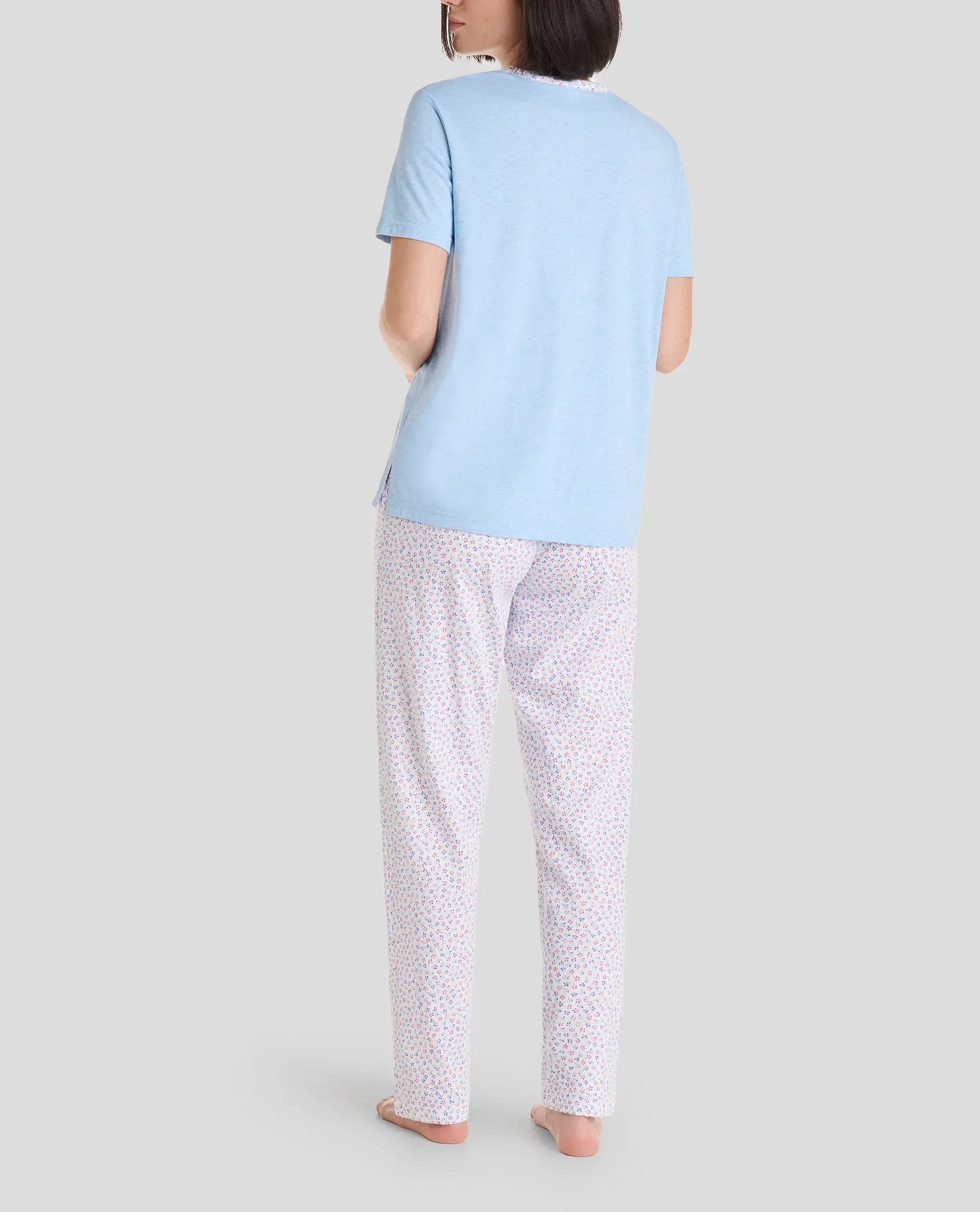 Vista de espaldas de mujer con pijama largo de verano con camiseta azul de manga corta y pantalón de forecitas con lazo rosa