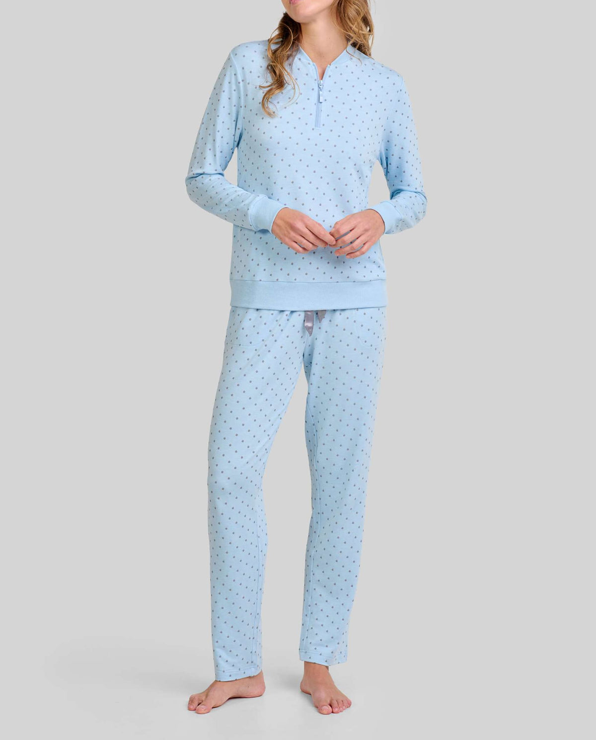 Mujer con cálido pijama largo celeste en tejido vigoré con estampado de pequeños topos grises