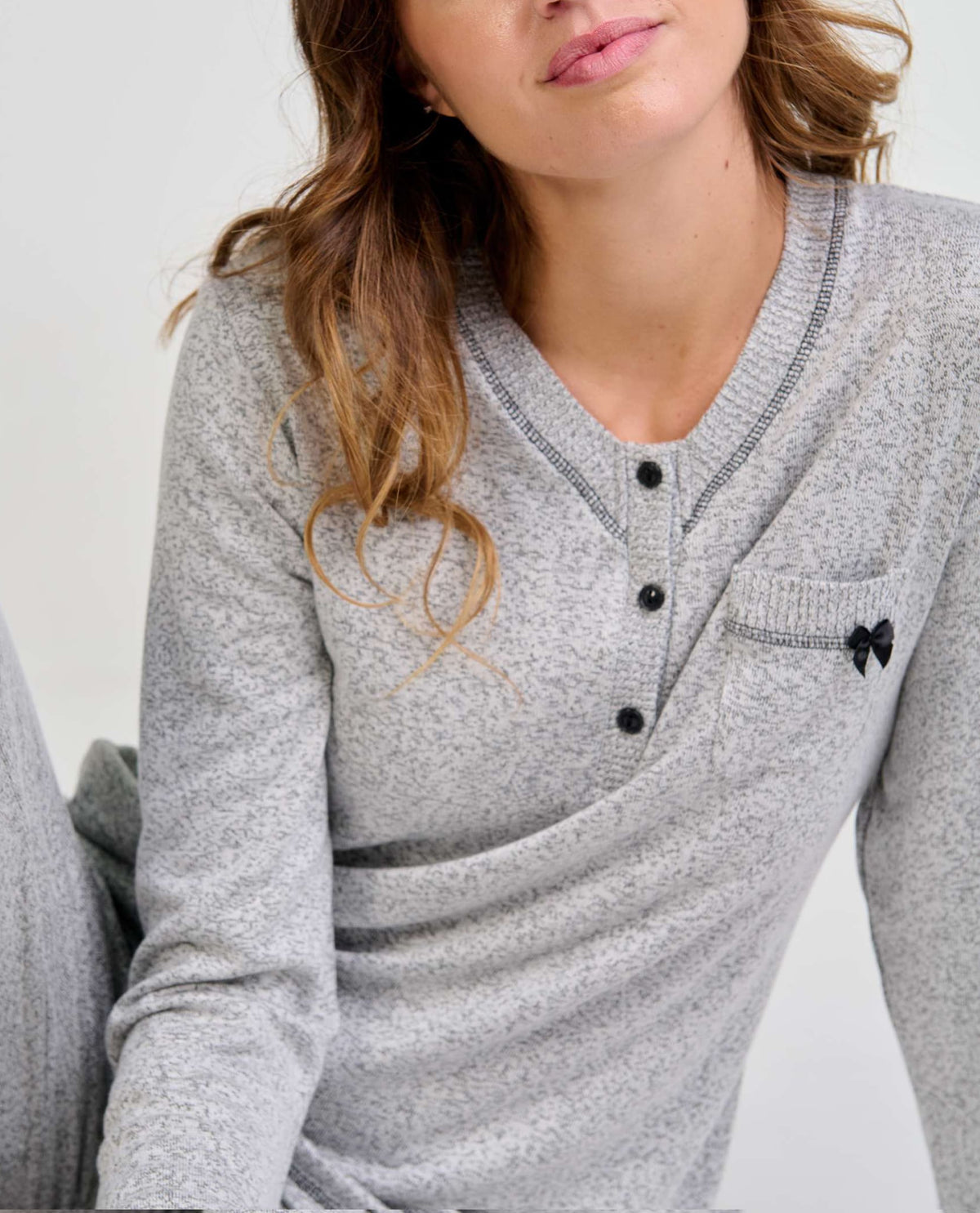 Mujer con pijama gris de manga larga y cuello con botones ideal para noches cómodas y descanso reparador.
