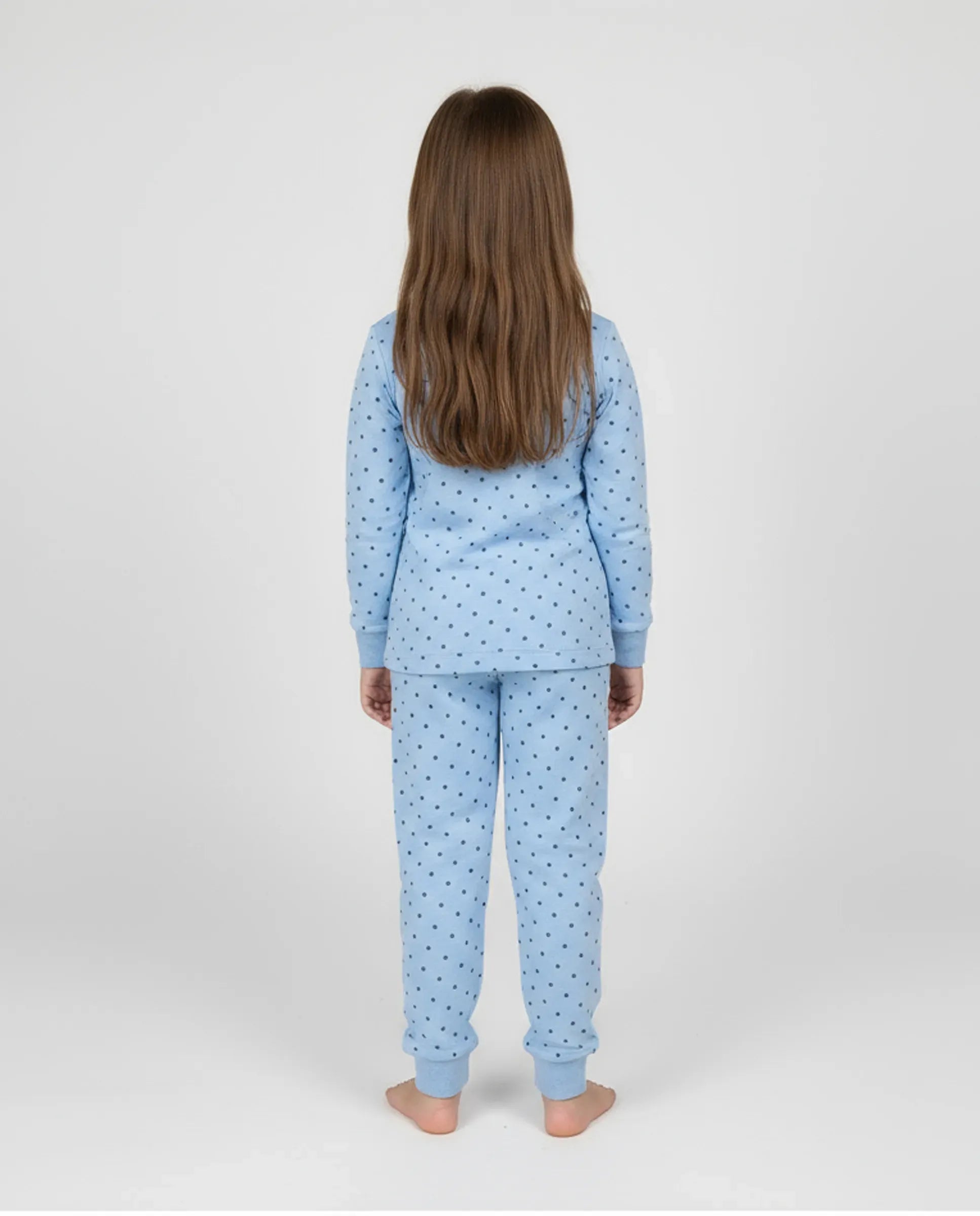 Niña de espaldas con cómodo y calentito pijama de invierno azul claro con topitos grises