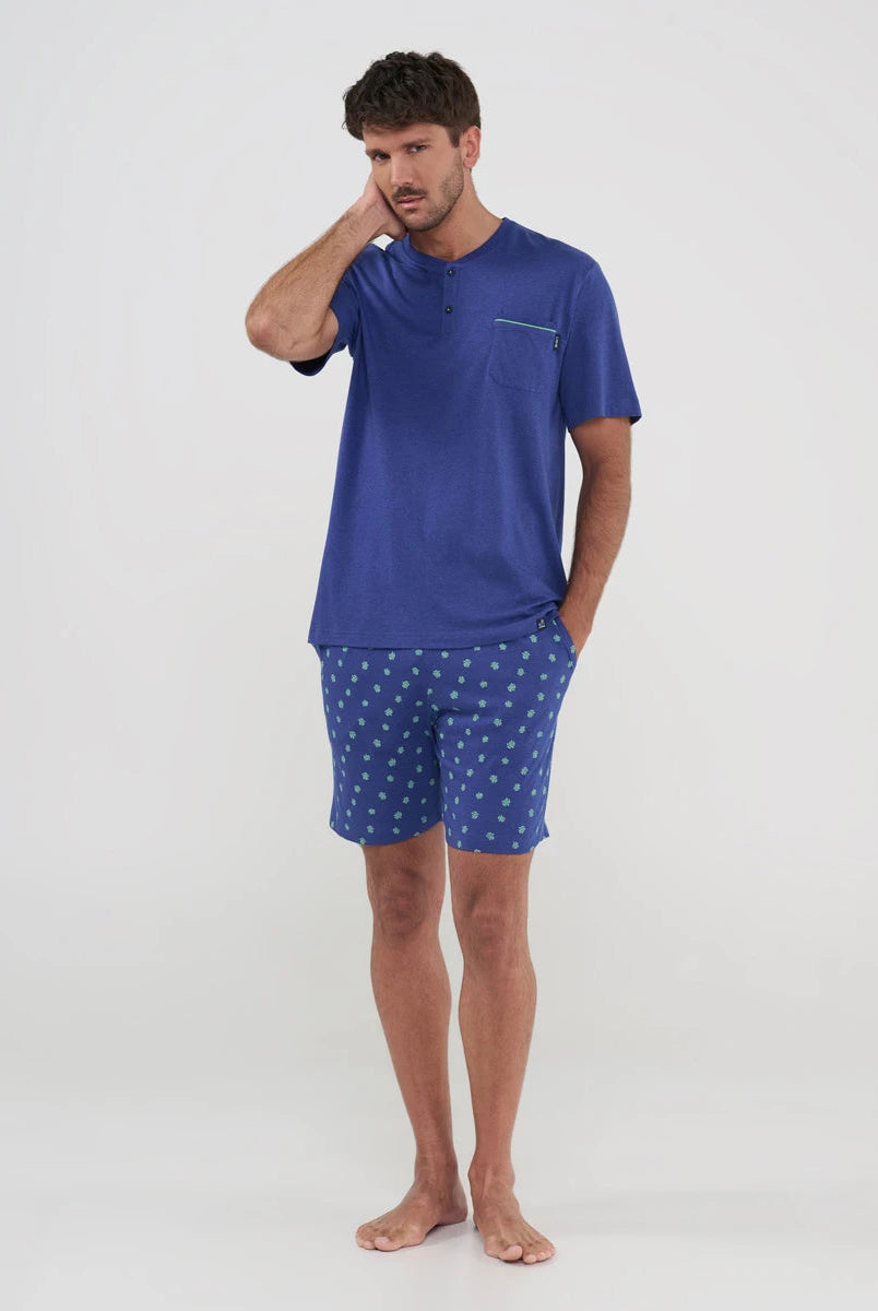hombre posa con pijama corto veraniego de color azul con pantalón corto de tortuguitas y bolsillos