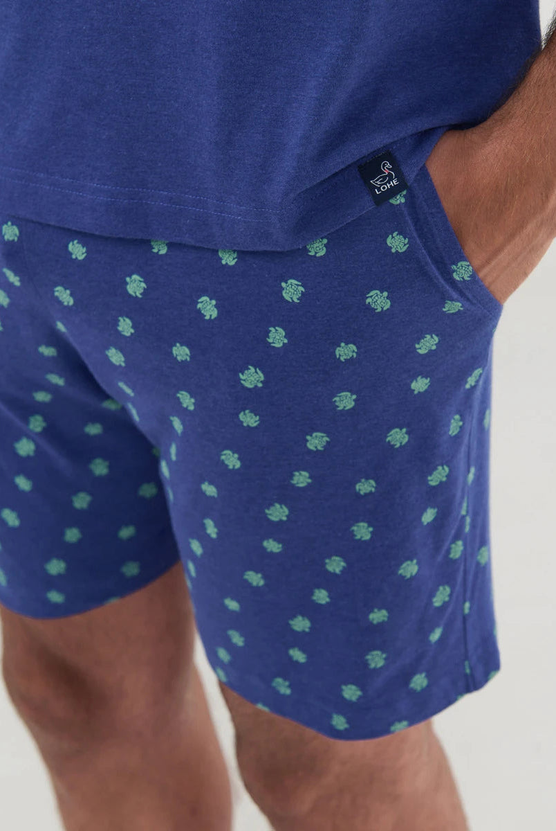 Detalle de pantalón de pijama azul con pequeñas tortugas verdes y bolsillos laterales