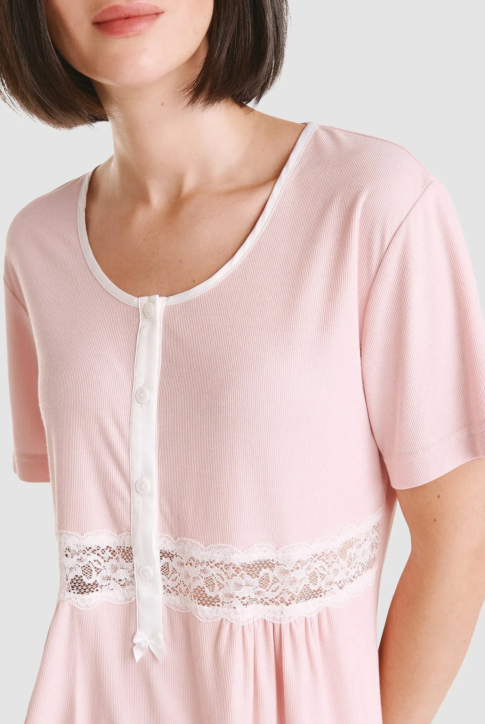 Vista detalle de chaquetilla de pijama lencero rosa de manga corta cuello redondo con pata, botones y puntilla en cintura