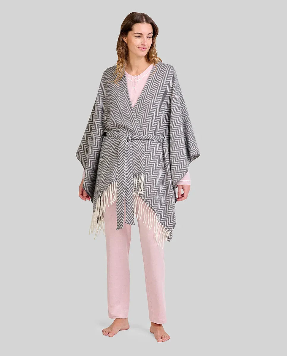 Mujer con pijama rosa claro y poncho gris con flecos y cinturón