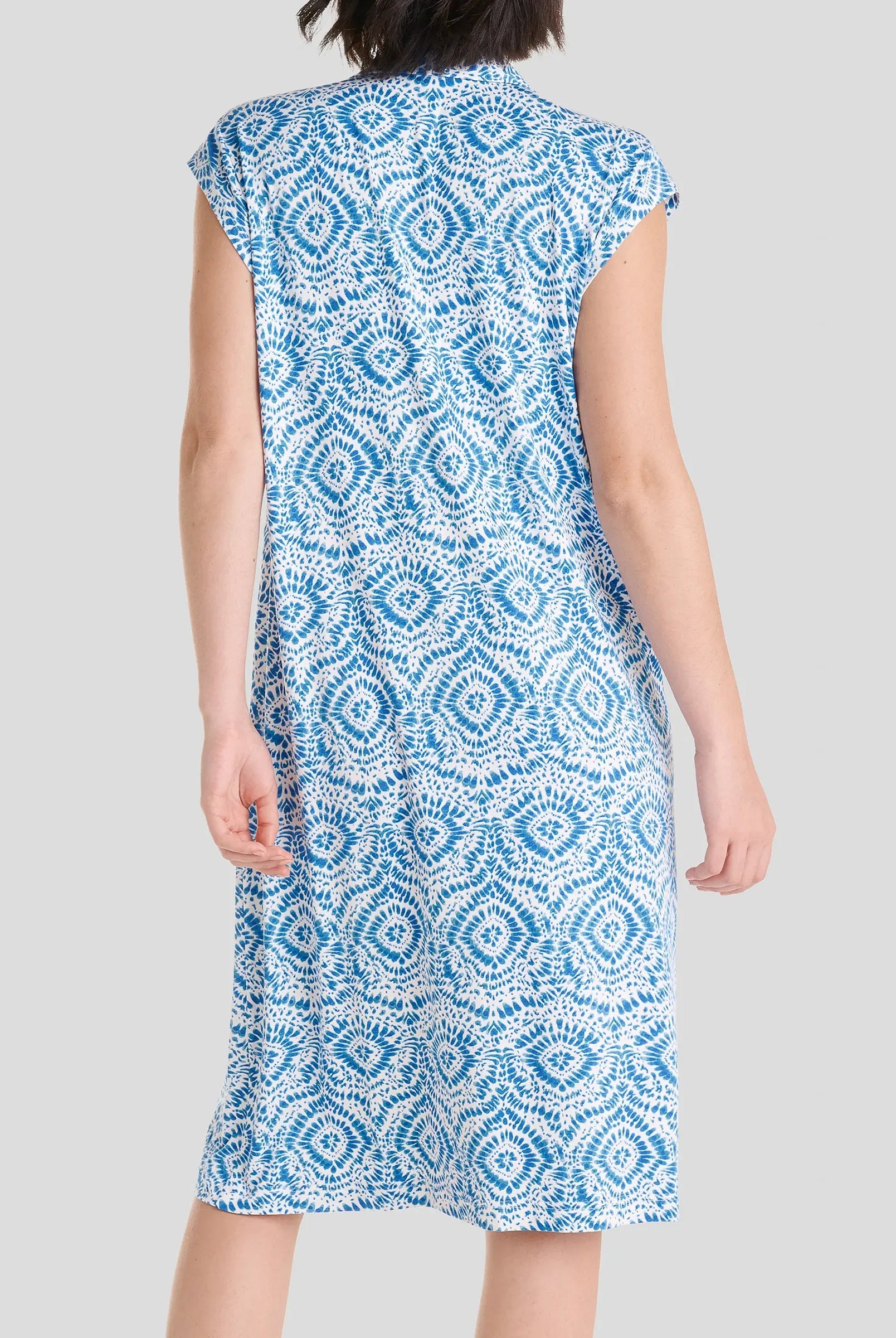 Vista de espaldas mujer luciendo un vestido sin mangas hasta la rodilla con un diseño geométrico en azul y blanco