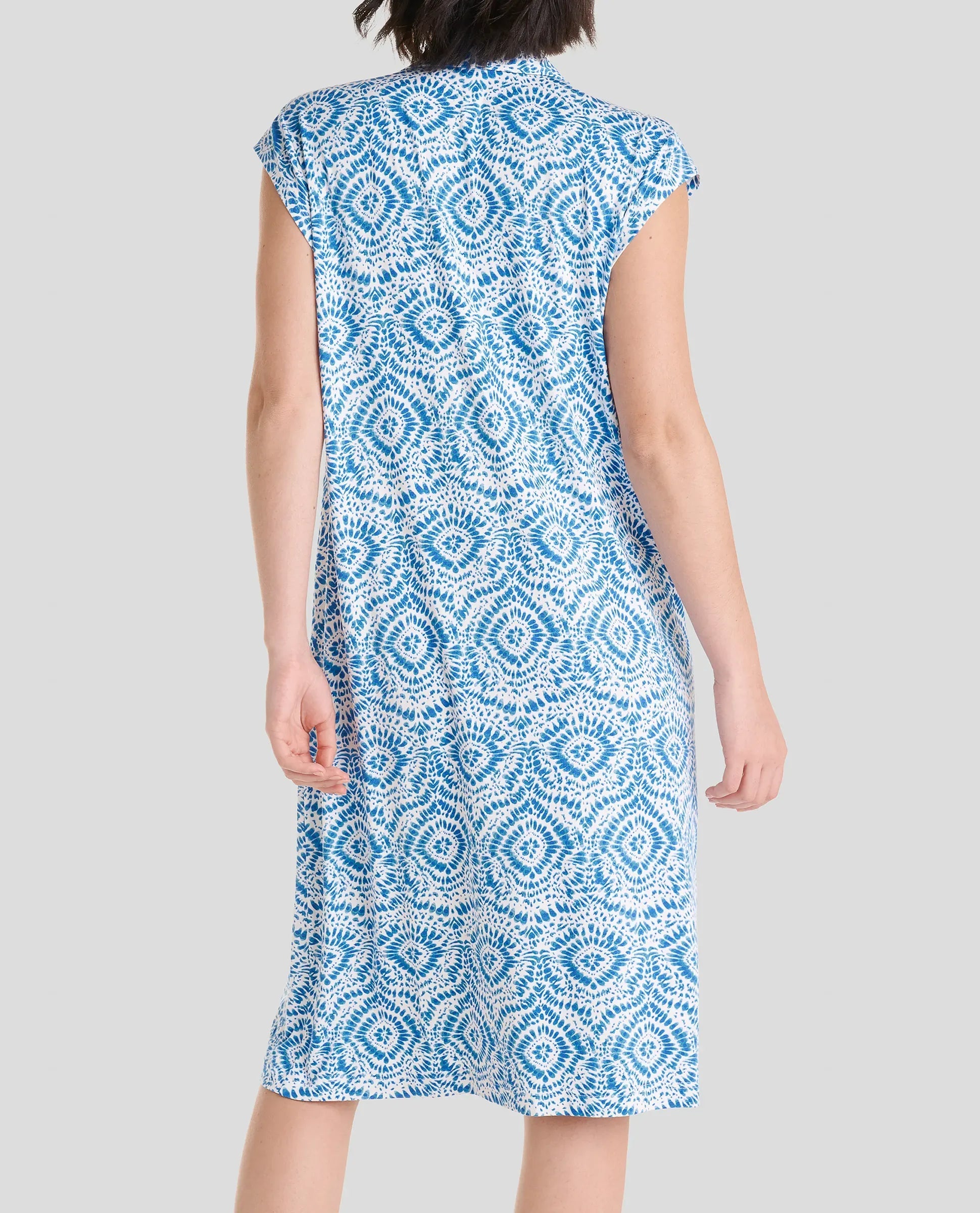 Vista de espaldas mujer luciendo un vestido sin mangas hasta la rodilla con un diseño geométrico en azul y blanco