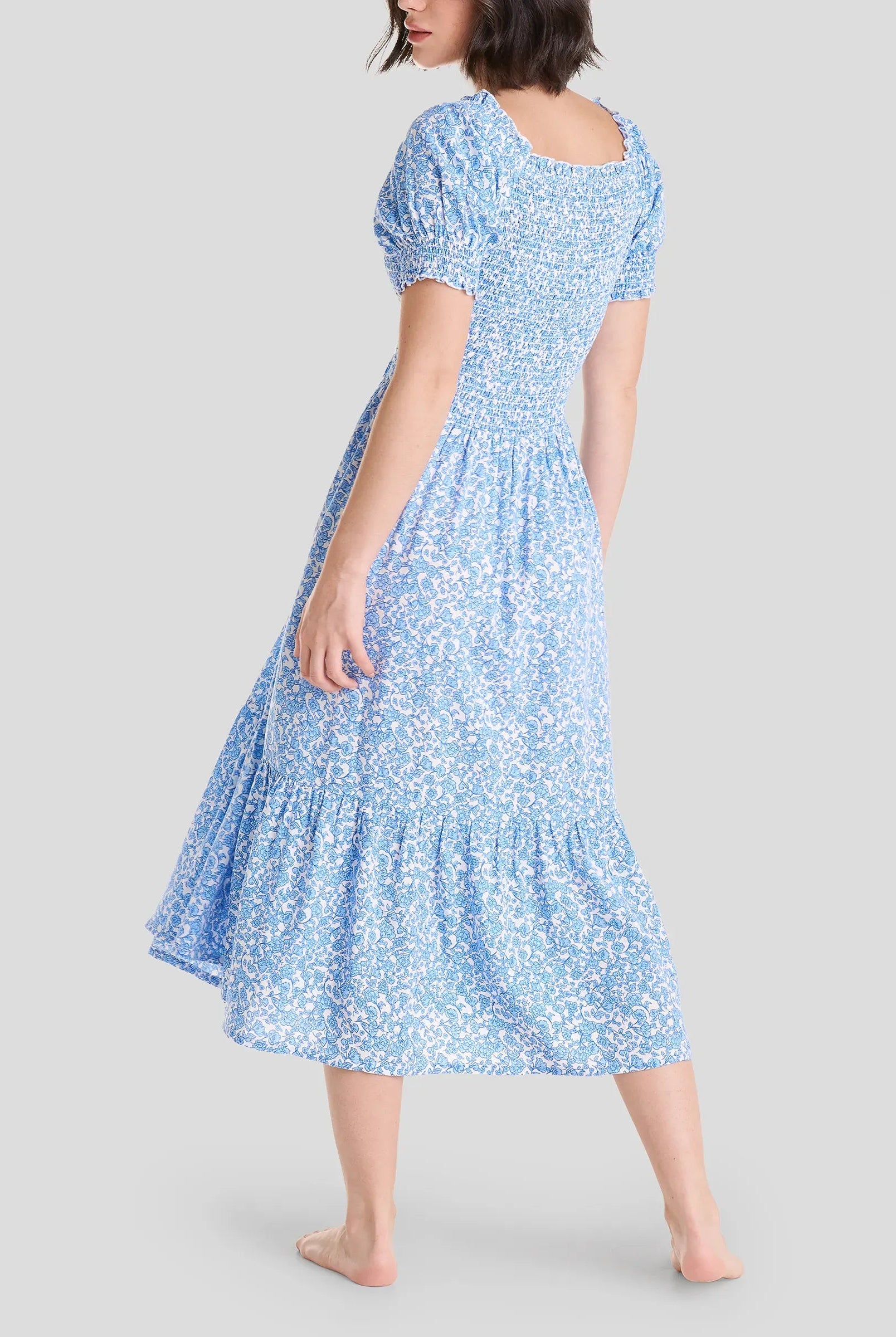 Vista trasera de mujer con vestido de verano hasta la rodilla estampado azul de flores y manga corta