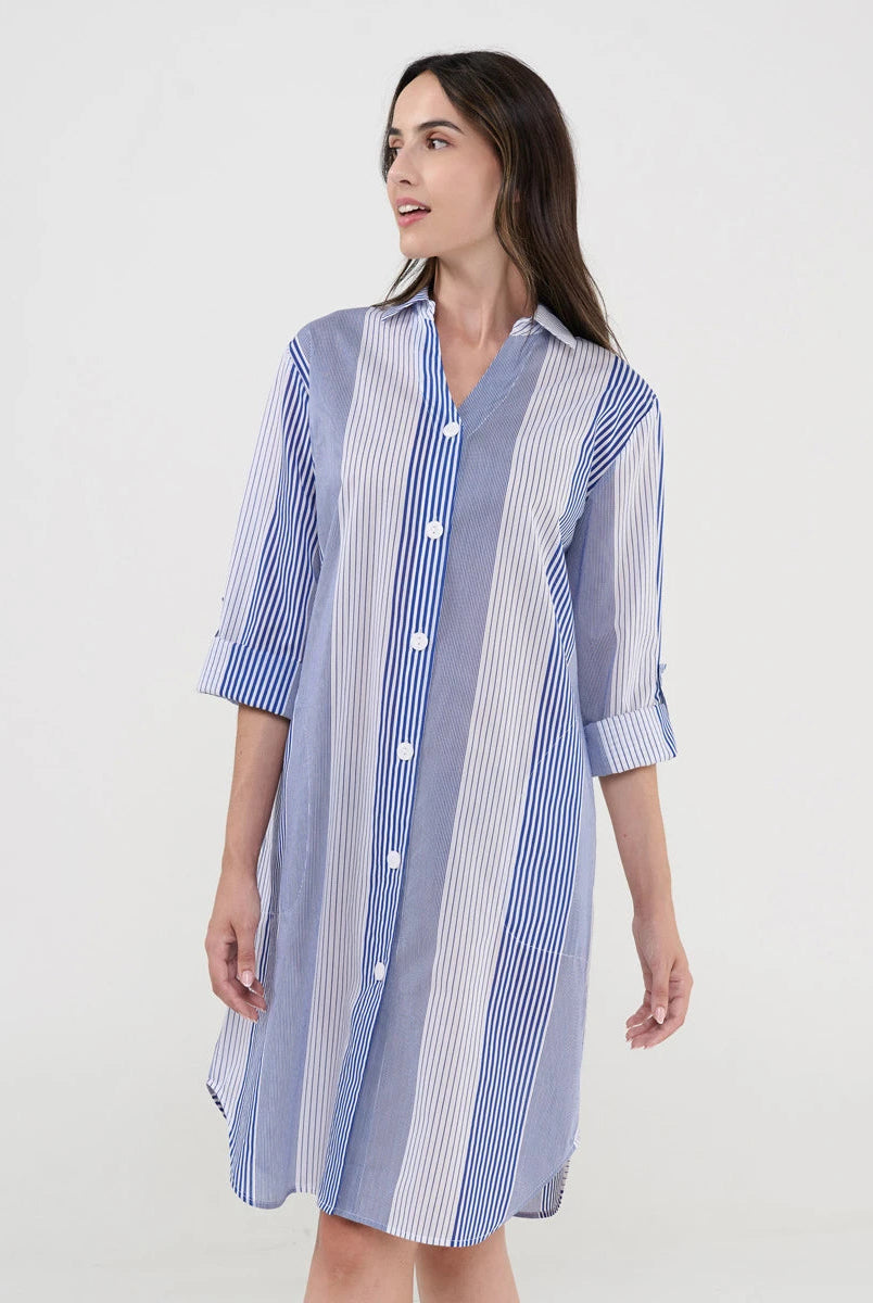 Mujer luce vestido camisero midi a rayas azules y blancas con botones blancos y mangas tres cuartos.