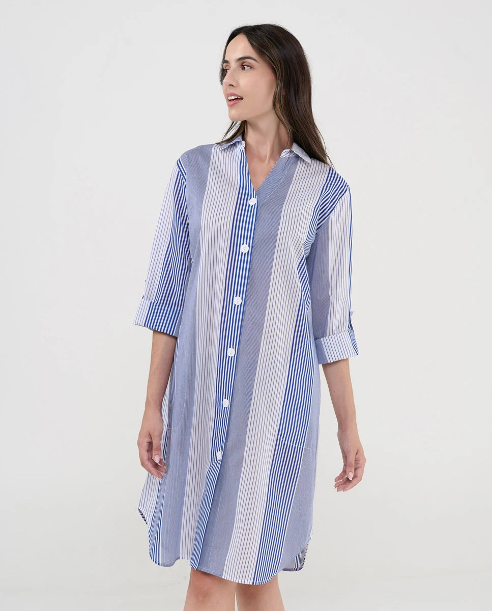 Mujer luce vestido camisero midi a rayas azules y blancas con botones blancos y mangas tres cuartos.