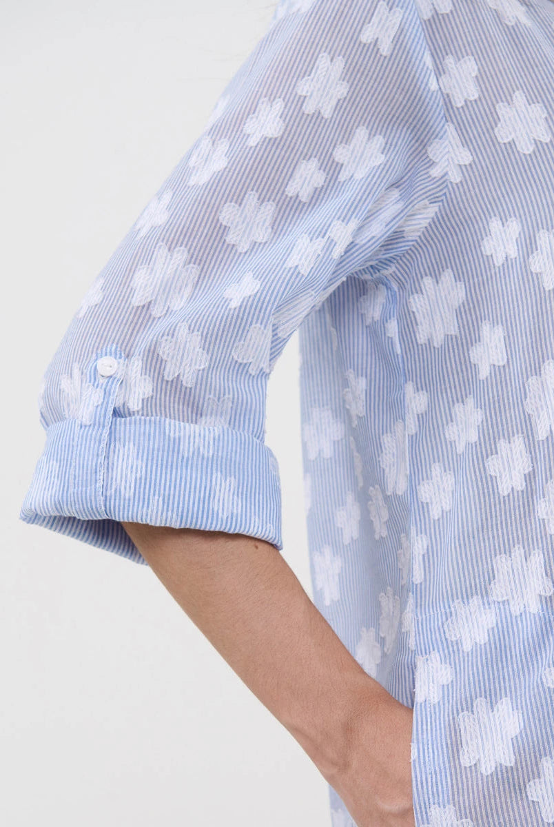 Detalle de manga arremangada y botón del vestido playero a rayas con flores blancas bordadas