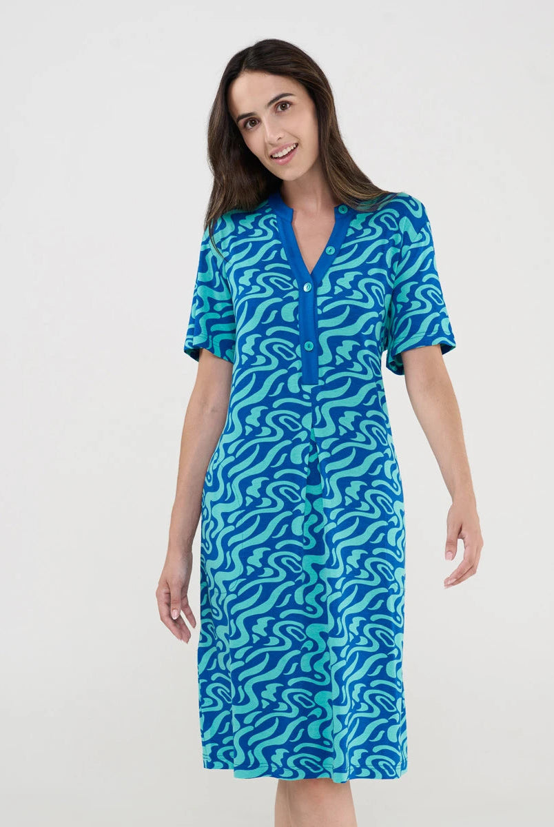 Mujer luce vestido veraniego corto de manga corta estampado azul ondas y cuello con botones