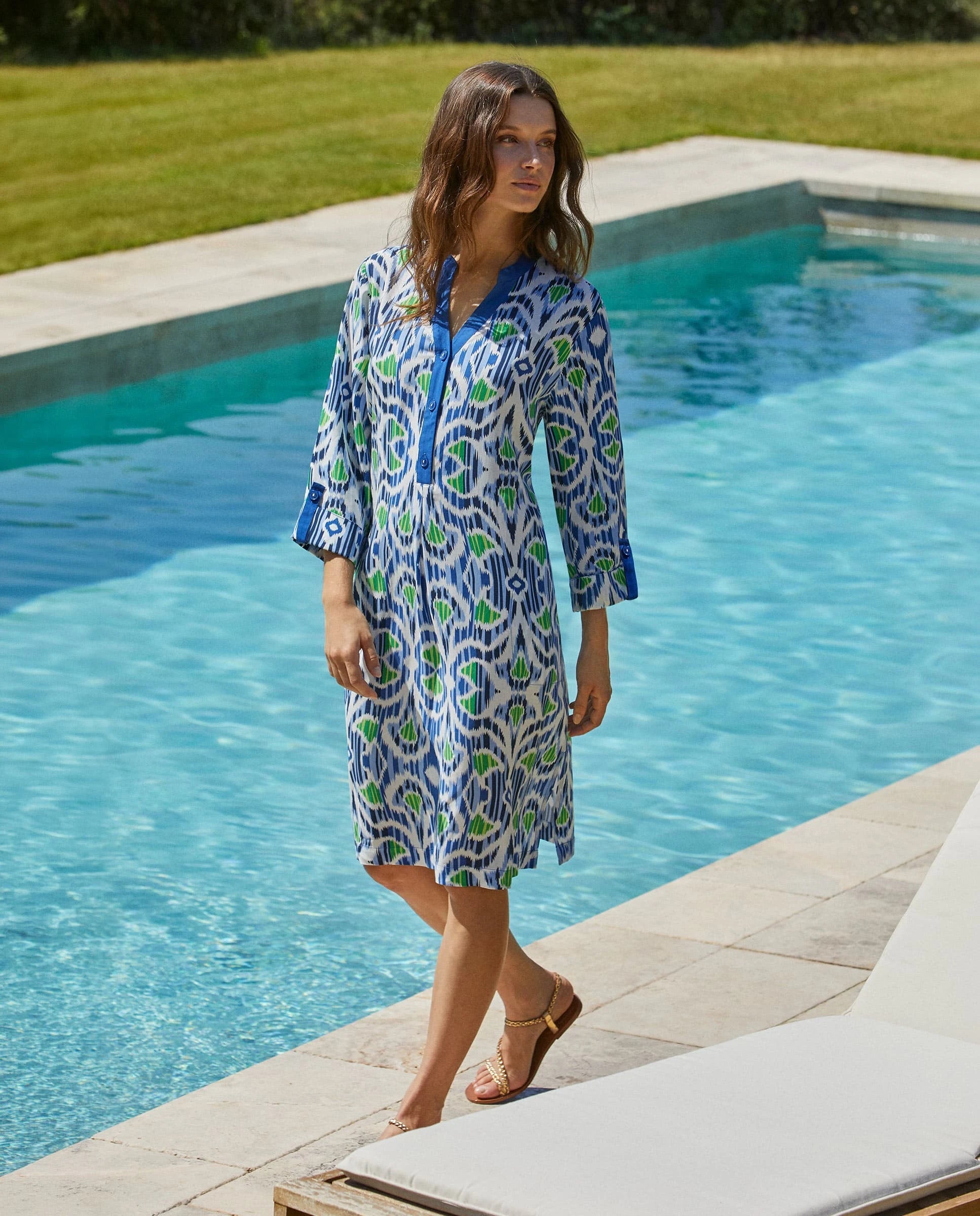 Mujer con vestido midi holgado con estampado étnico en azul, verde y blanco, cuello en V con botones y mangas tres cuartos.