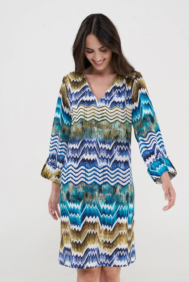 Mujer con vestido midi de estampado chevrón en tonos azul, turquesa y dorado con escote en V y mangas tres cuartos.