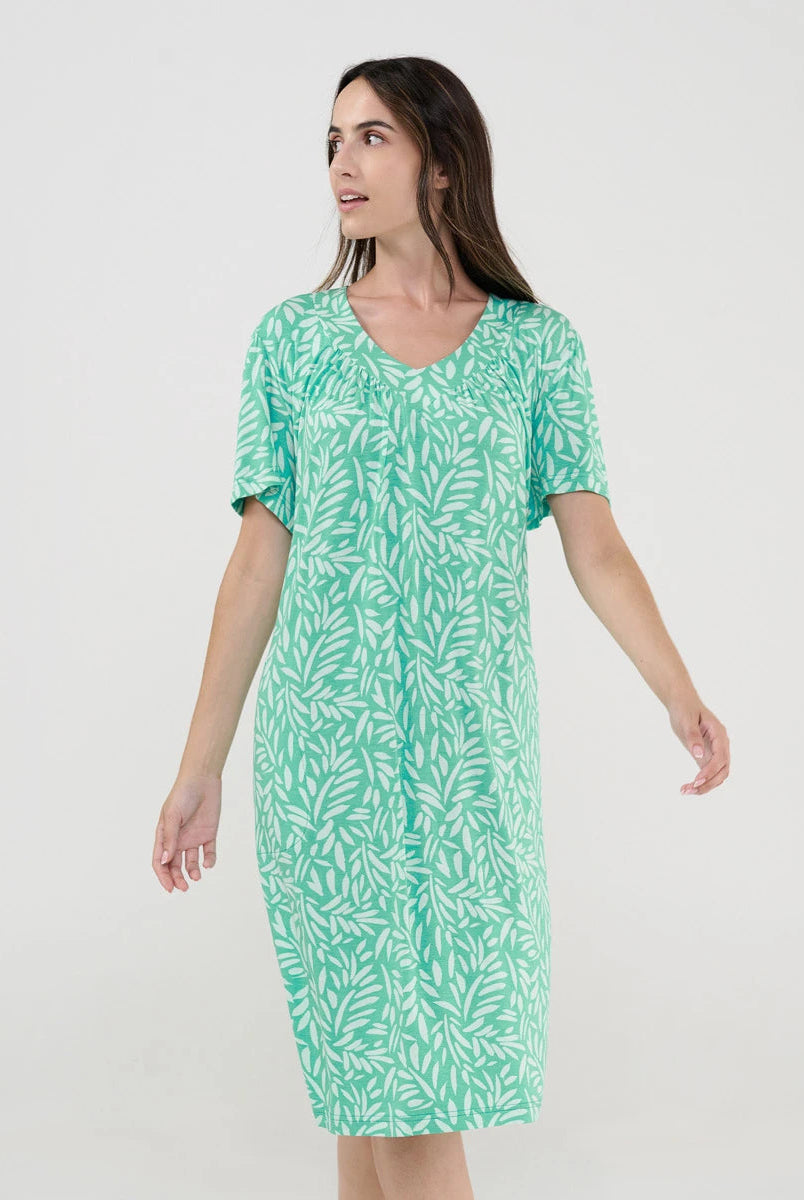 Mujer posando con vestido de baño verde de manga corta y estampado de hojas.