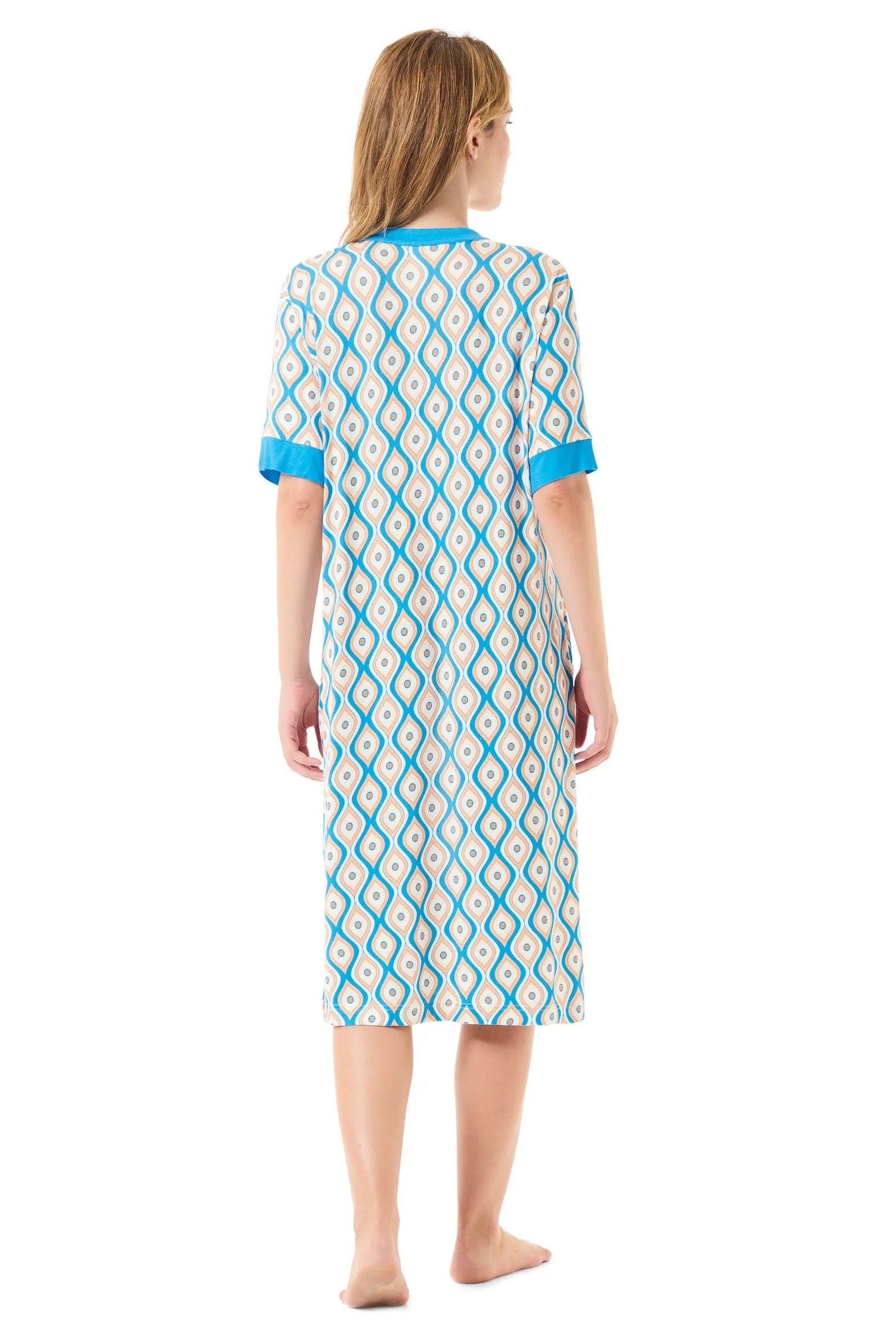 Una mujer descalza de espaldas luce un vestido de longitud media con estampado y detalles en azul en las mangas y el cuello.
