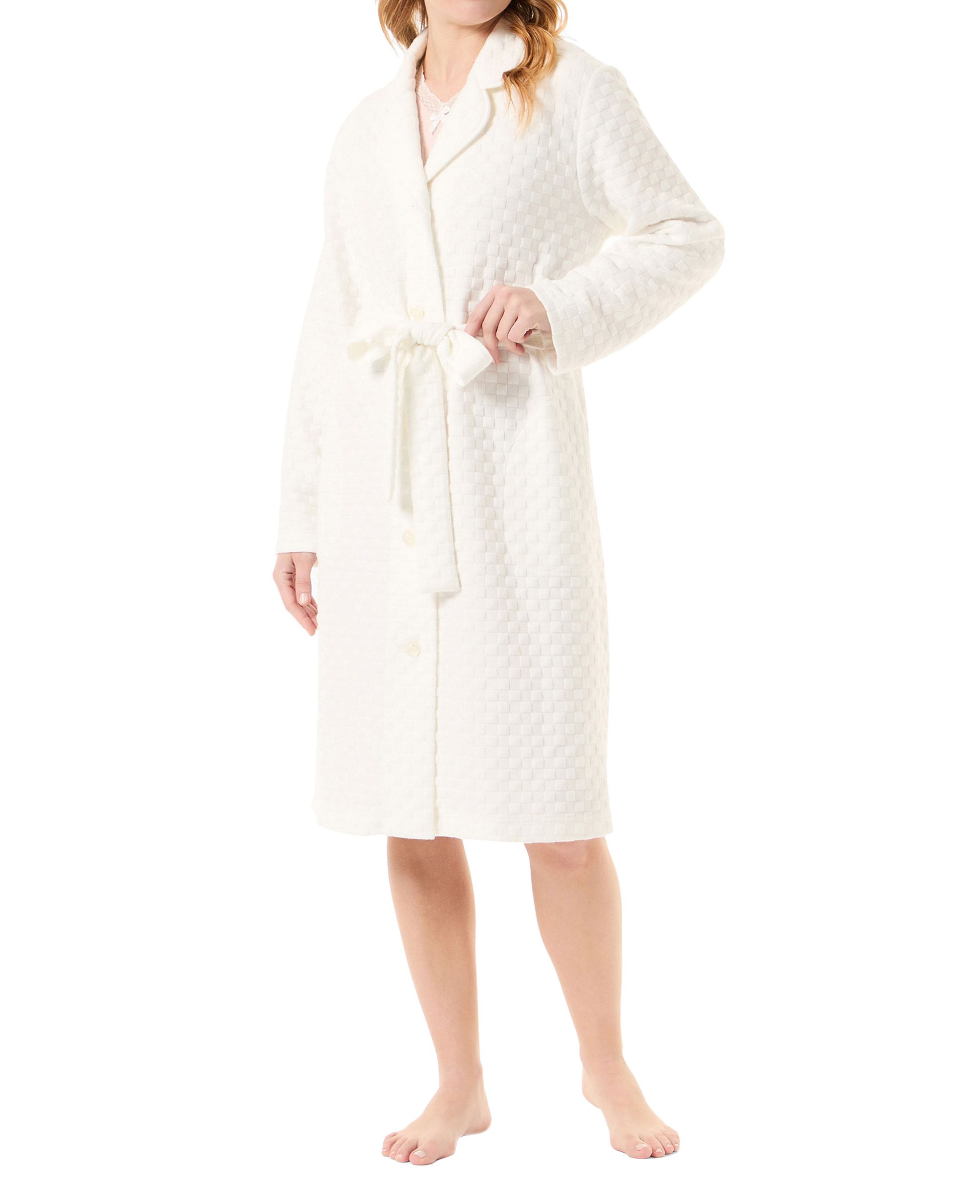 Woman in ivory-coloured open long dressing gown with circular knitted buttons