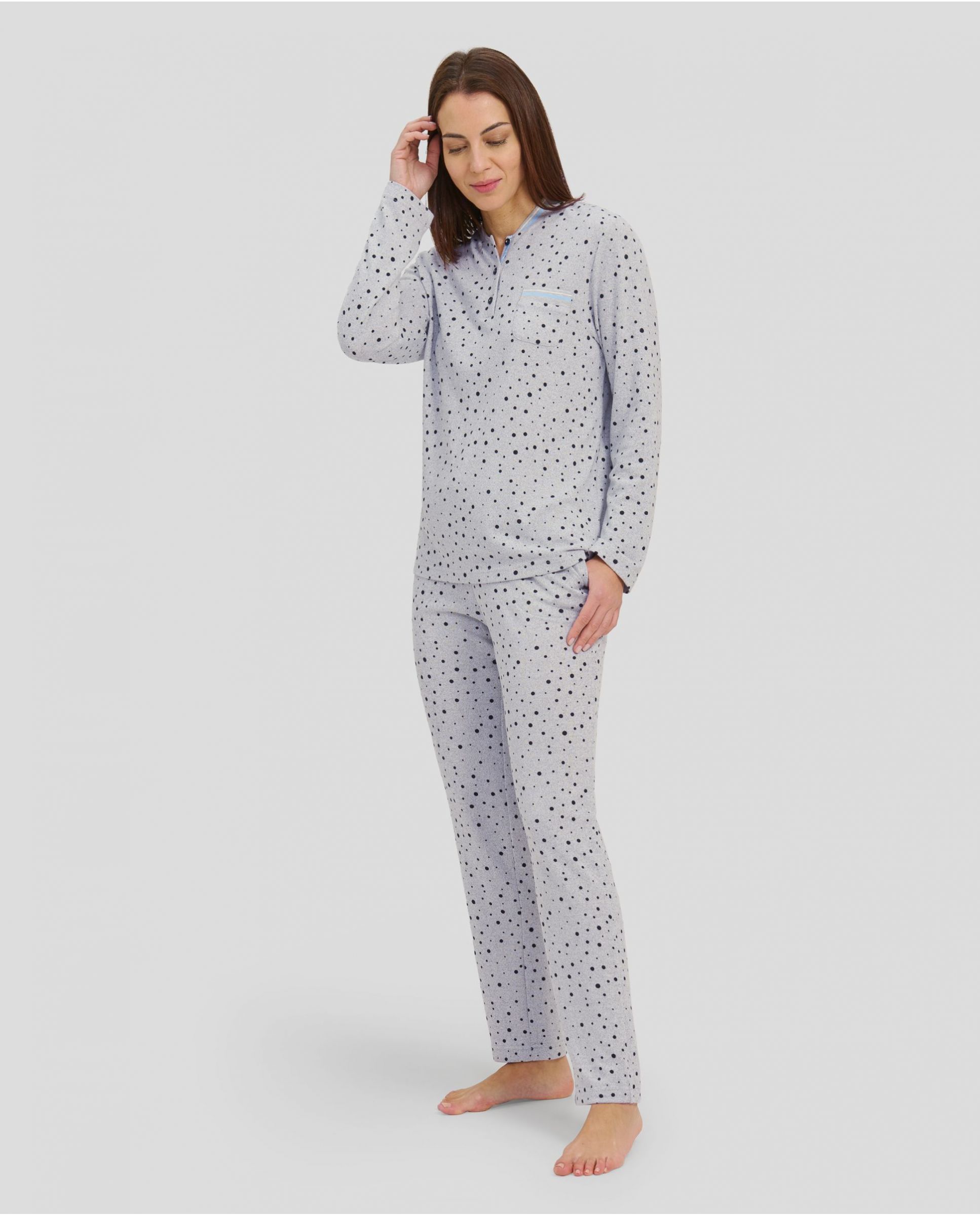 Woman with long-sleeved winter pyjamas in grey taupe with polka dot pattern