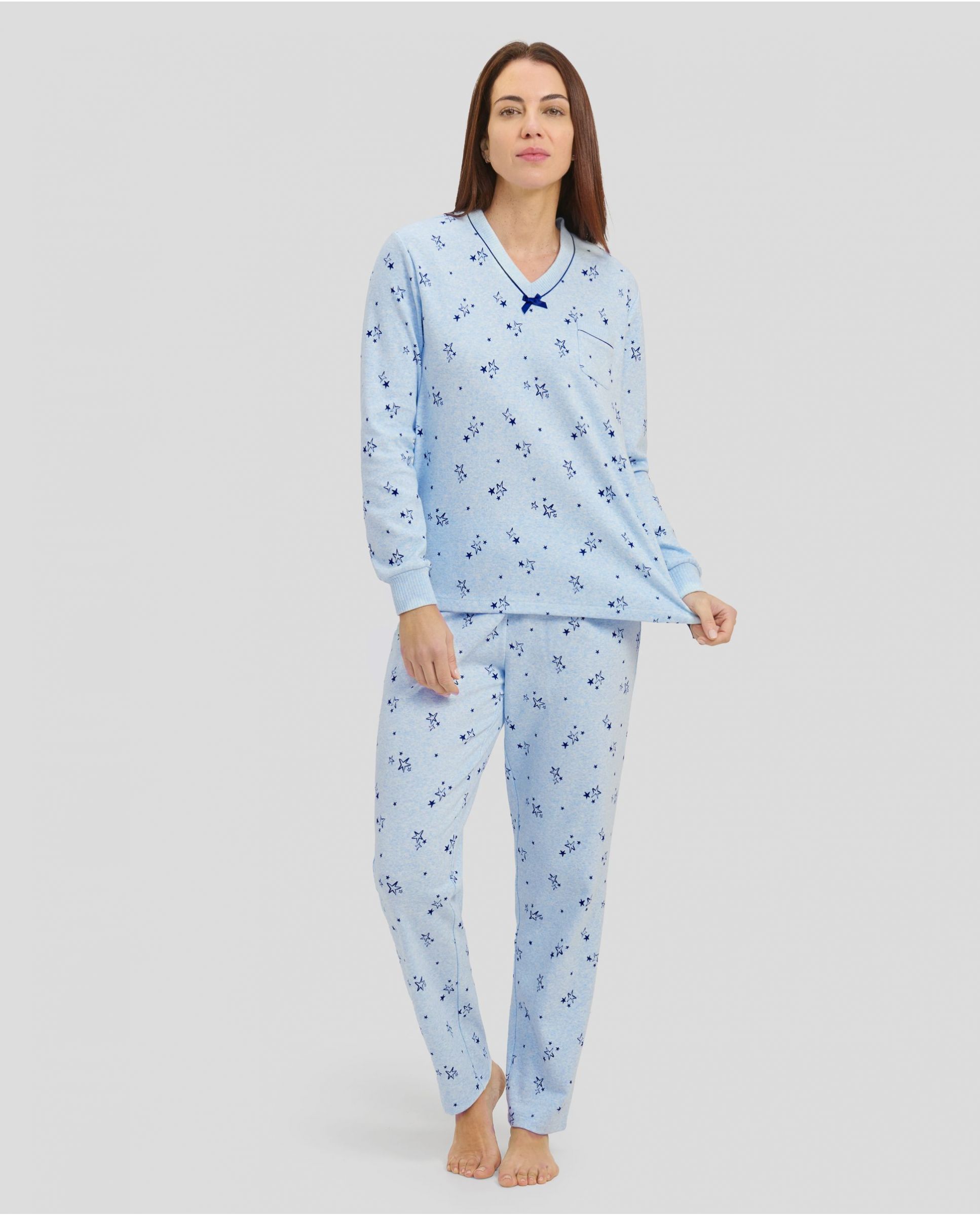 Woman in light blue long-sleeved winter pyjamas with stars and V-neck with bow decoration