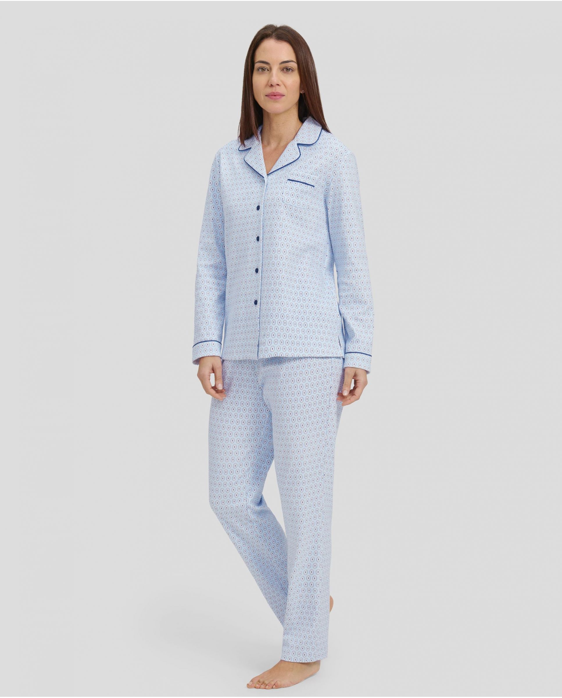 Woman in light blue shirt pyjamas with buttoned ovals and contrasting piped collar.