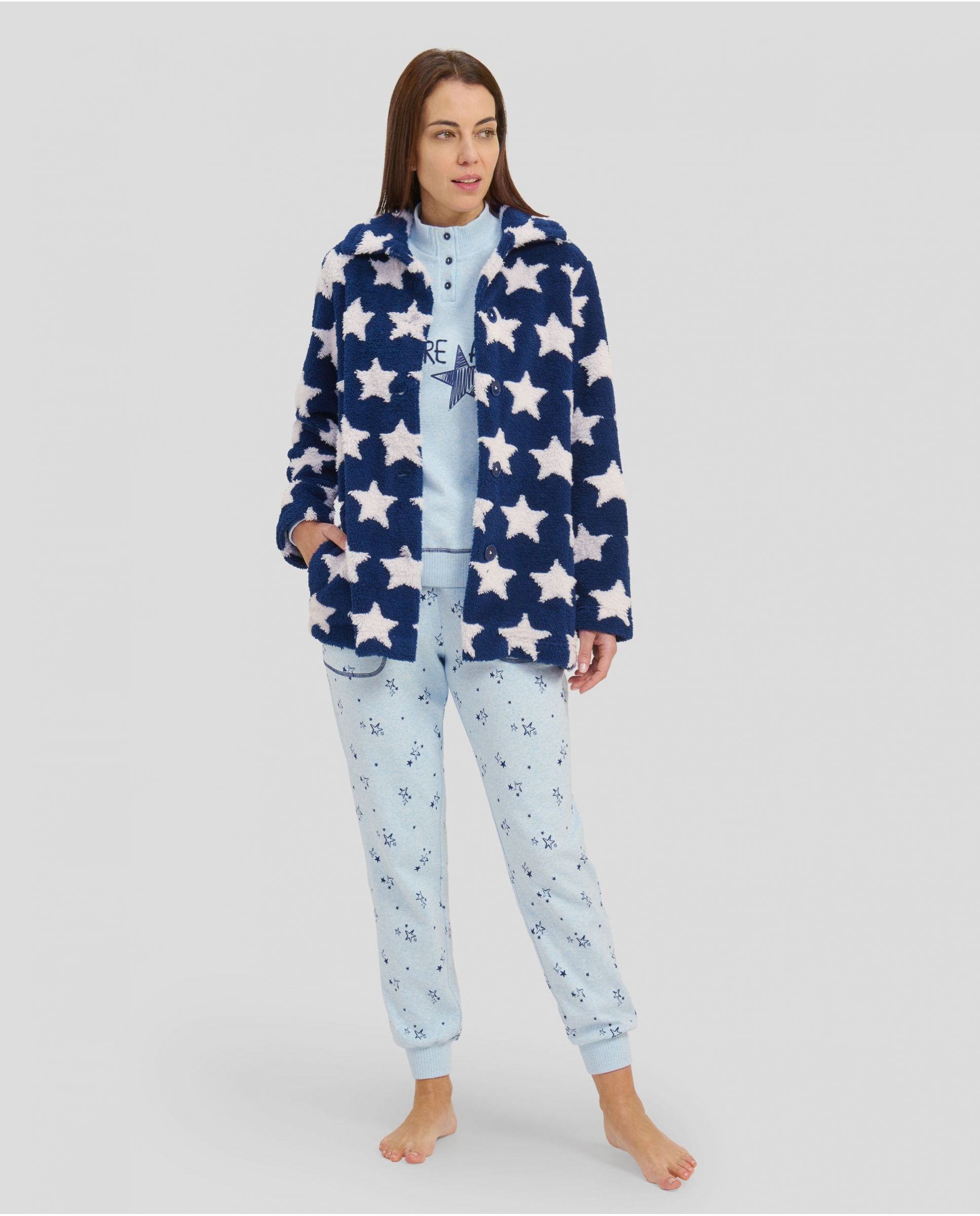 Woman wearing a set of winter pyjamas and short dressing gown in shades of blue and stars.