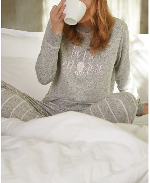 Young woman in winter pyjamas drinking coffee in bed