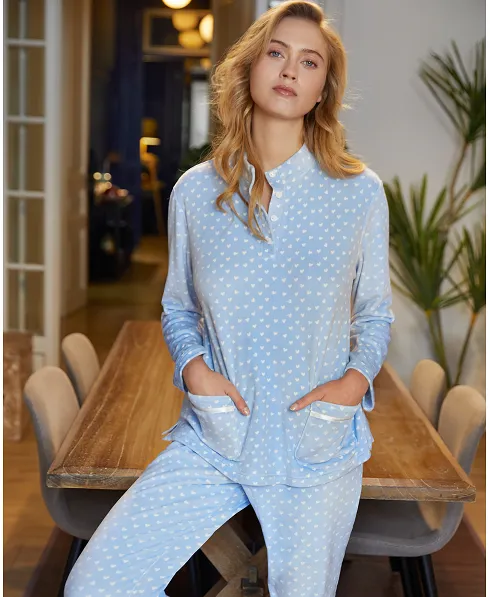 Model with light blue women's tracksuit, heart print, open band collar with buttons and pockets.