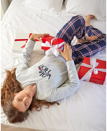 Cheerful woman resting in bed in her Lohe Christmas pyjamas