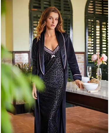 Woman in leopard long nightdress, V-neck with lace, pink bow and thin shoulder straps, matching black velvet dressing gown