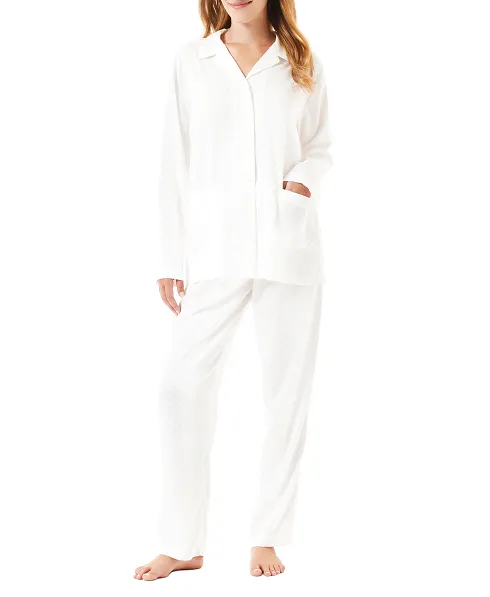 A woman wears an ivory jacquard printed long pyjama set open with buttons.