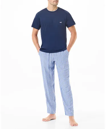 Un hombre vistiendo pijama con pantalón a rayas y una camiseta azul marino.