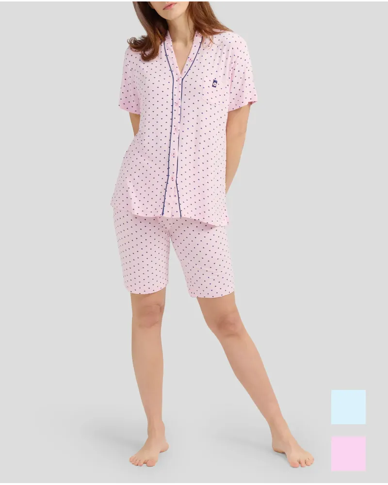 A woman wears a pink short-sleeved pyjama set with little hearts.
