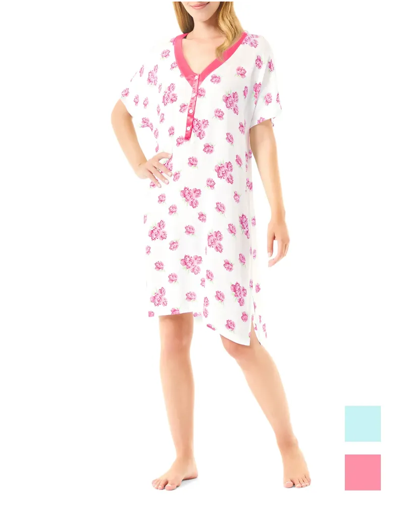 Una mujer luciendo un camisón corto blanco con flores color fucsia y cuello de raso a juego.