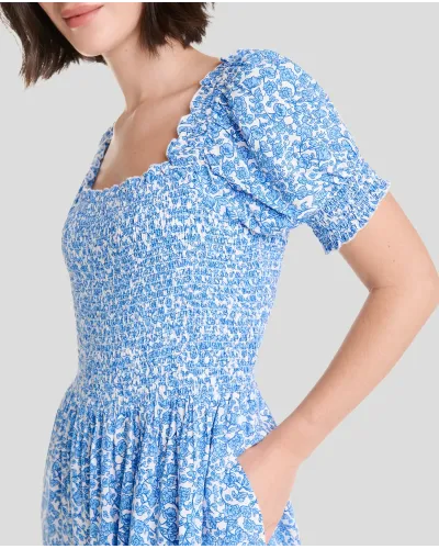Woman in long blue flowered dress with short sleeves, honeycomb top and square neckline