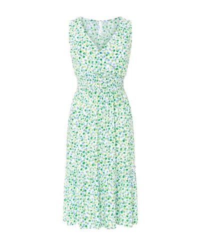 Model wears short sleeveless summer dress in pistachio green with polka dots and honeycomb waistband