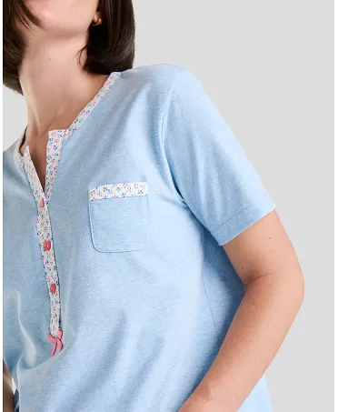 Detail of blue short-sleeved women's summer pyjama top with flower details, open collar with pink buttons and decorative pocket