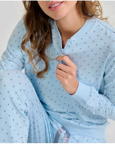 Woman wearing warm, long, sky blue pyjamas in a twill fabric with a small grey polka dot print.