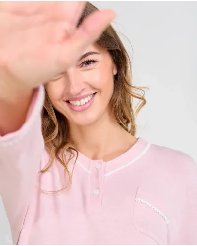 Woman wearing long pink melange winter pyjamas with a V-neck decorated with white trim