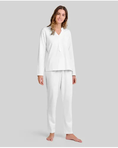 Woman wearing ivory-coloured long nightdress pyjamas with an open neckline, lace trim and bow