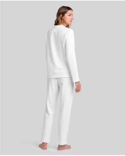 Woman wearing ivory-coloured long nightdress pyjamas with an open neckline, lace trim and bow