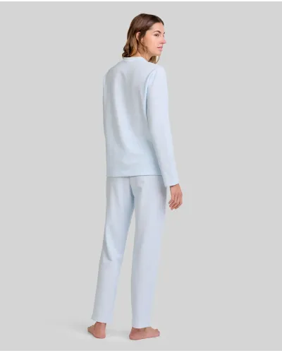 Woman wearing light blue long nightdress pyjamas with an open neckline, lace trim and bow