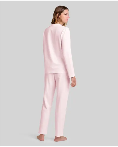 Woman wearing pale pink long nightdress pyjamas with open neckline, lace trim and bow