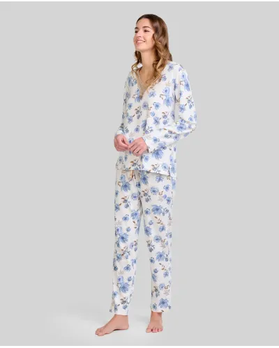Woman wearing long-sleeved pyjamas with a blue floral print and a V-neckline with lace detailing.
