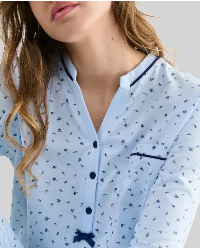Woman wearing long sky blue winter pyjamas with a floral print, button-up collar and pocket