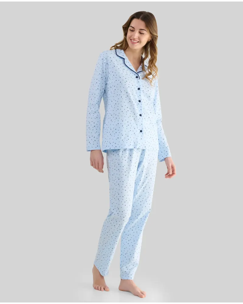 Woman wearing light blue long-sleeved pyjamas with buttons, small floral print and contrasting piping