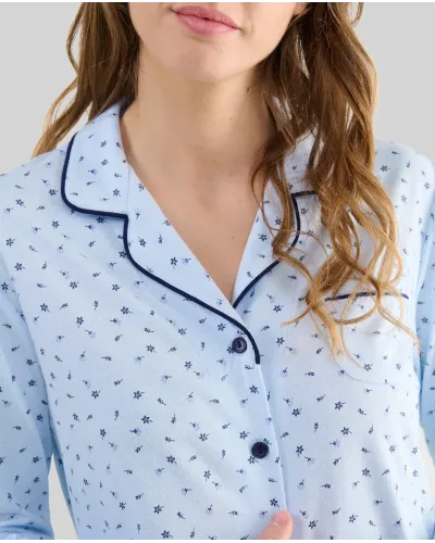 Woman wearing light blue long-sleeved pyjamas with buttons, small floral print and contrasting piping