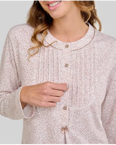 Woman wearing a long-sleeved, knee-length nightdress with a camel-coloured floral print and front buttons.